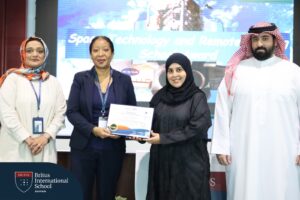 Three teachers, two women and a man, awarding a BRS-Labs student with a certificate. There is a logo that says "Britus International School Bahrain" in white text on a blue background.